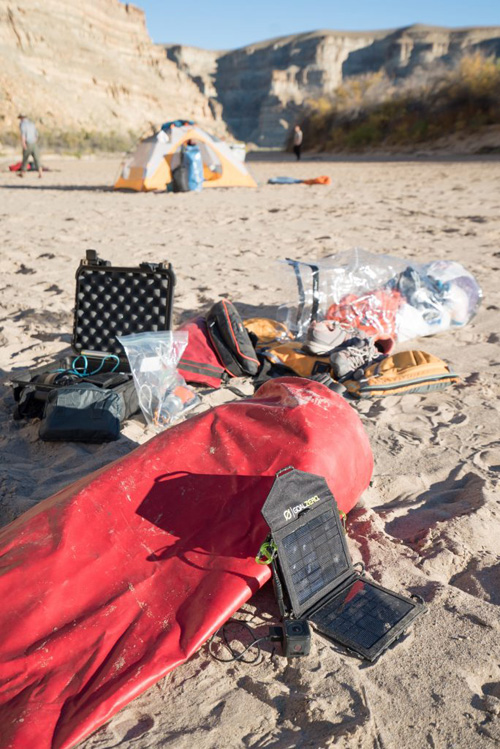 A solar charger charging an action camera on the edge of a river