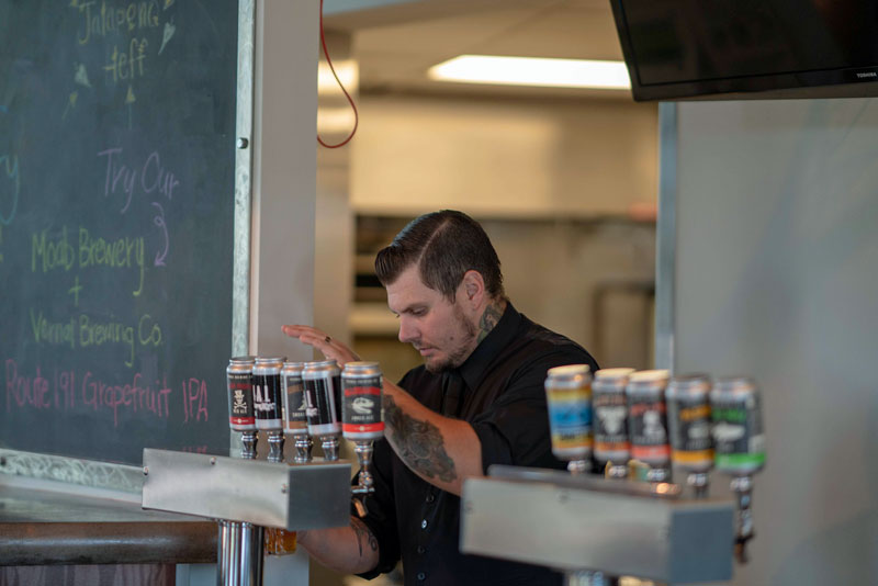 A man pours a beer from the taps at Vernal Brewing Company