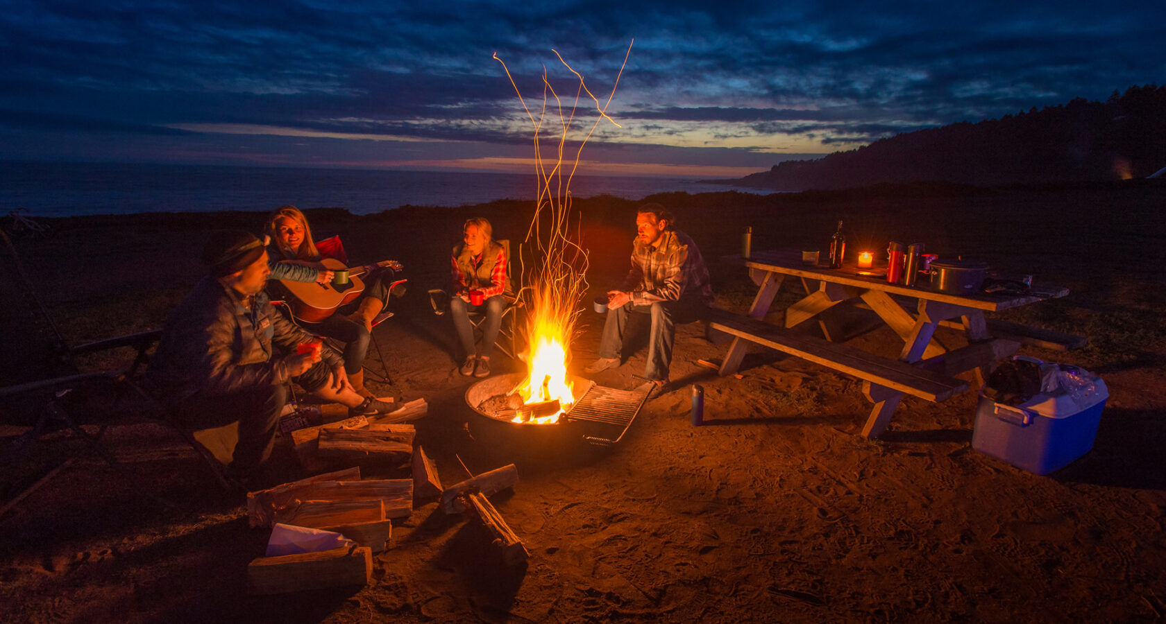 Friends gathering around a campfire at night