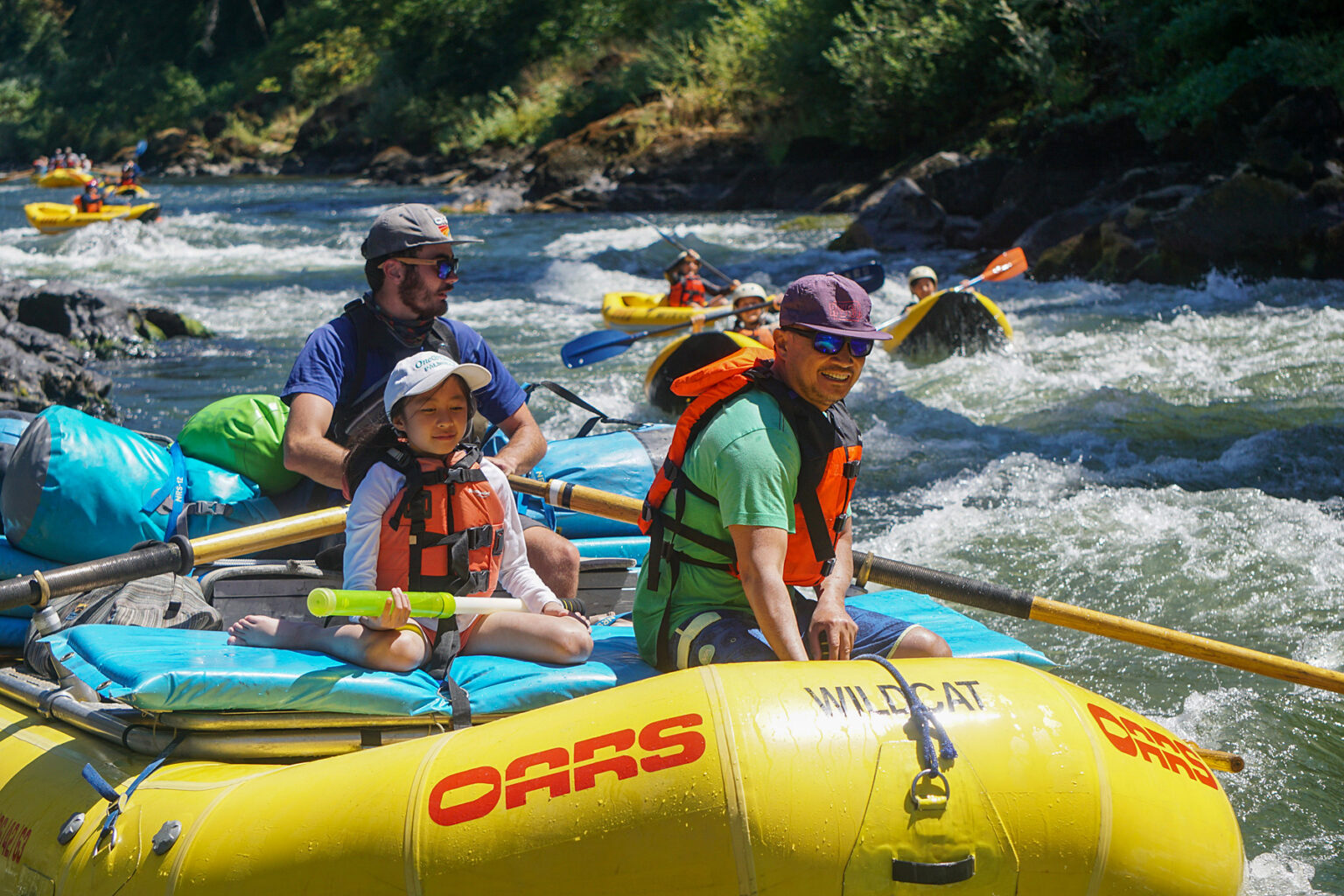 Asian American father and daughter aboard a yellow OARS raft on the Rogue River in Oregon