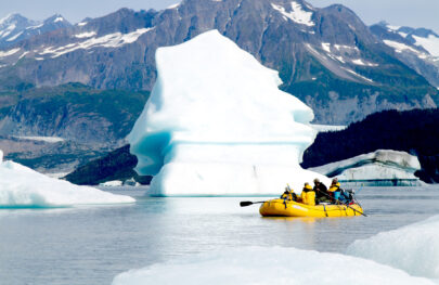 A raft floats by an iceberg on the Tatshenshini River