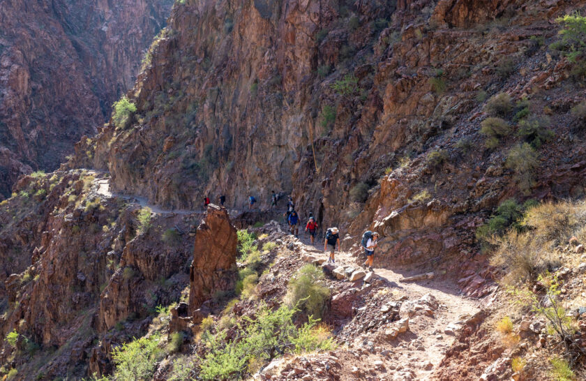 A group of hikers with large backpacks ascend the Bright Angel Trail in Grand Canyon