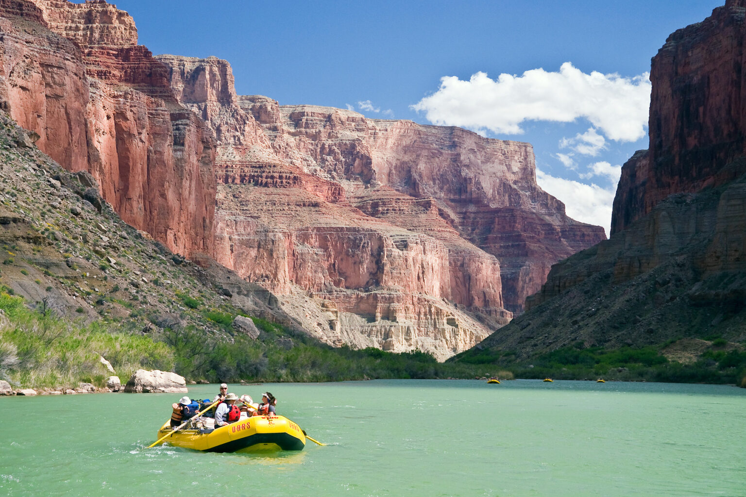 Yellow raft green river pink cliffs blue sky Grand Canyon