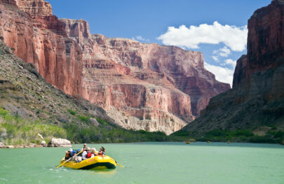 Yellow raft green river pink cliffs blue sky Grand Canyon