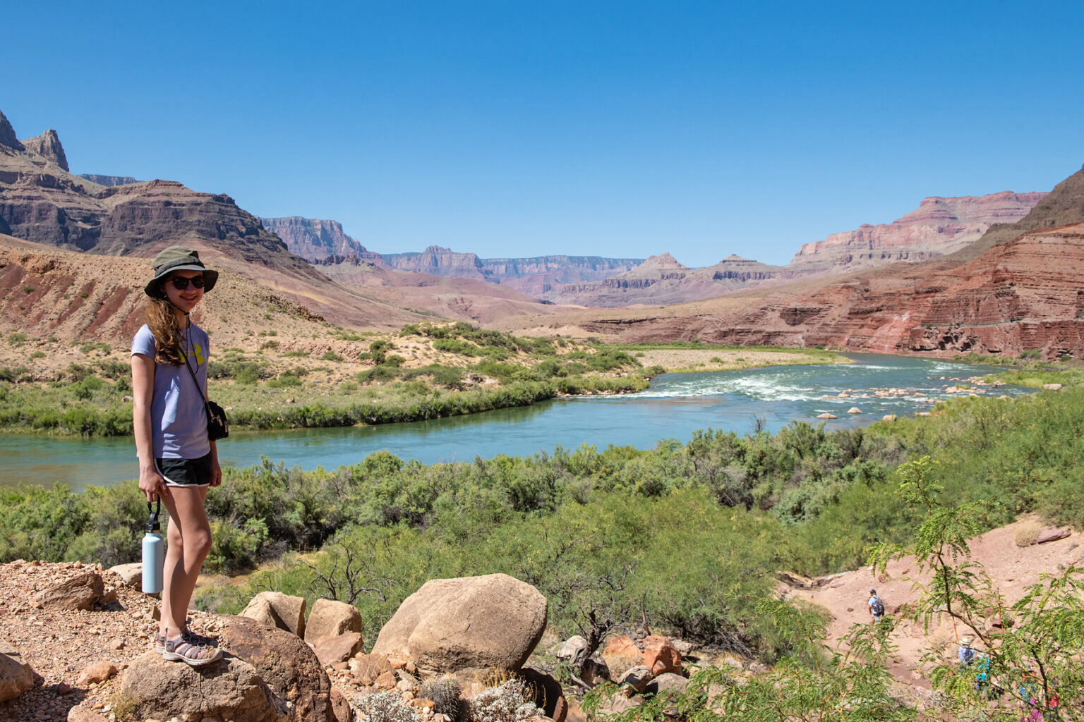 Girl poses for camera with tamarisk-lined Colorado River in background