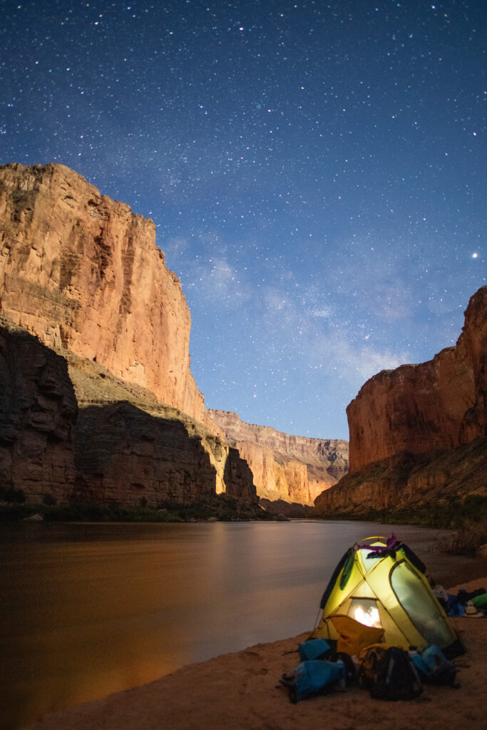 Illuminated tent pitched next to the Colorado River in Grand Canyon