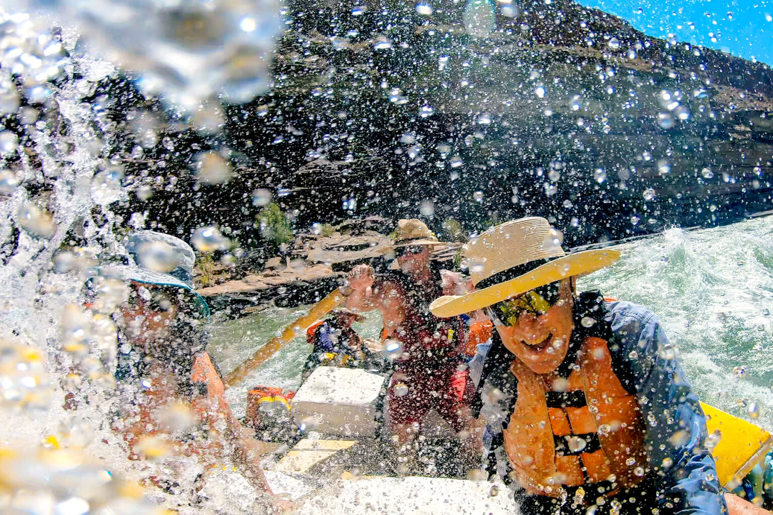Happy guest in straw hat gets wet in whitewater Grand Canyon
