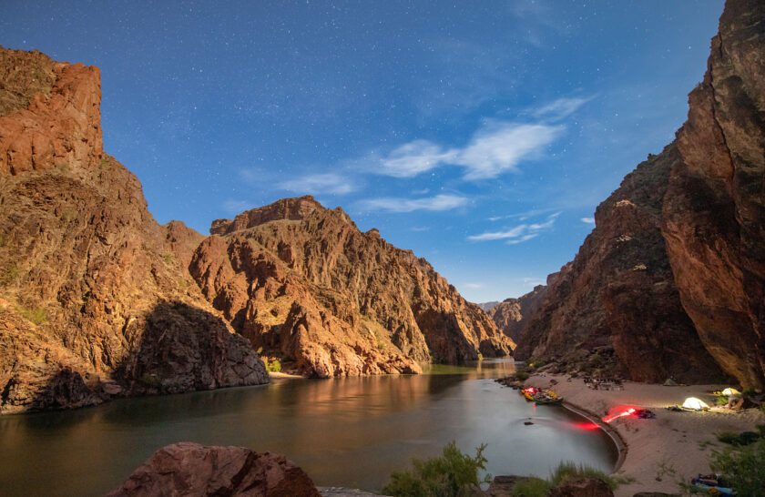 Timelapse shot of OARS camp in evening in Grand Canyon with glowing tents and stars