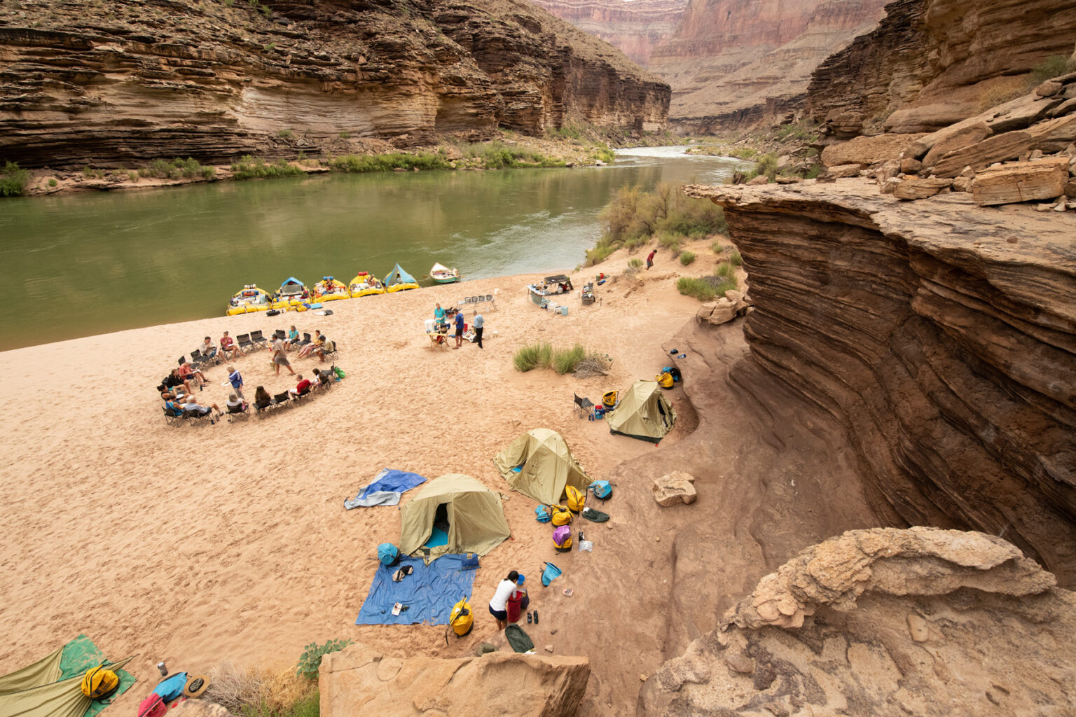 OARS camp from above in Grand Canyon showing moored boats, chair circle, kitchen and tents