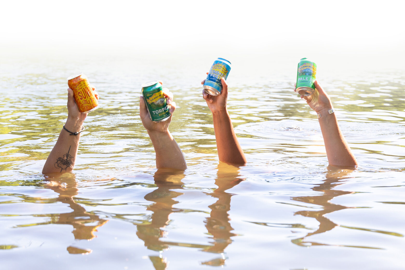 Hands in the river holding up craft beer.