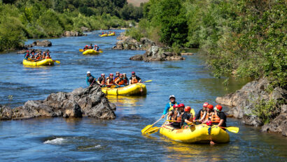 Several yellow rafts full of paddlers spread out on the South Fork of the American River in California