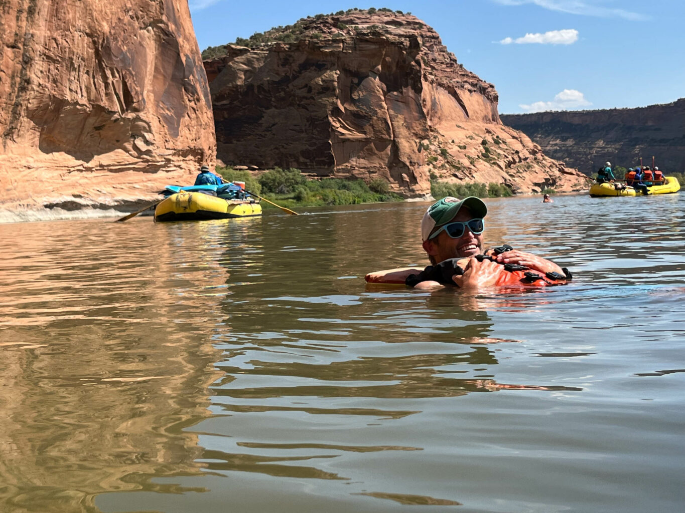 Man floating in a river with a group of rafters.