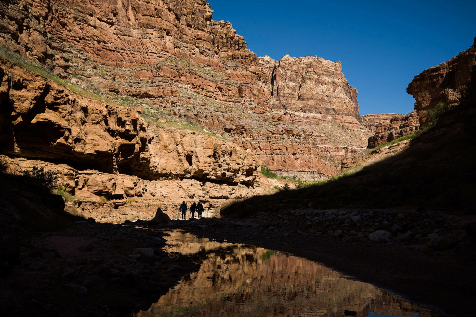 Hikers exploring Lower Dark Canyon during a guided Cataract Canyon rafting trip in Utah with OARS.
