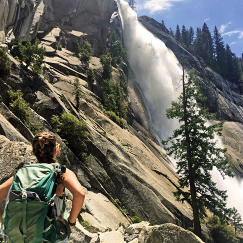 Woman enjoying a view of a waterfall in Yosemite.