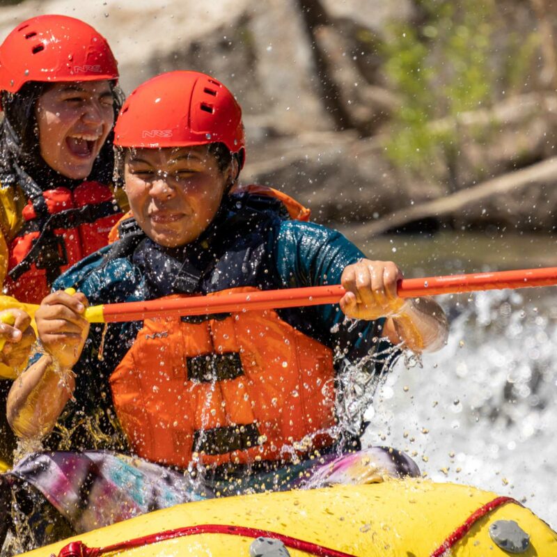 A group of people white water rafting at the Barking Dog Rapid.