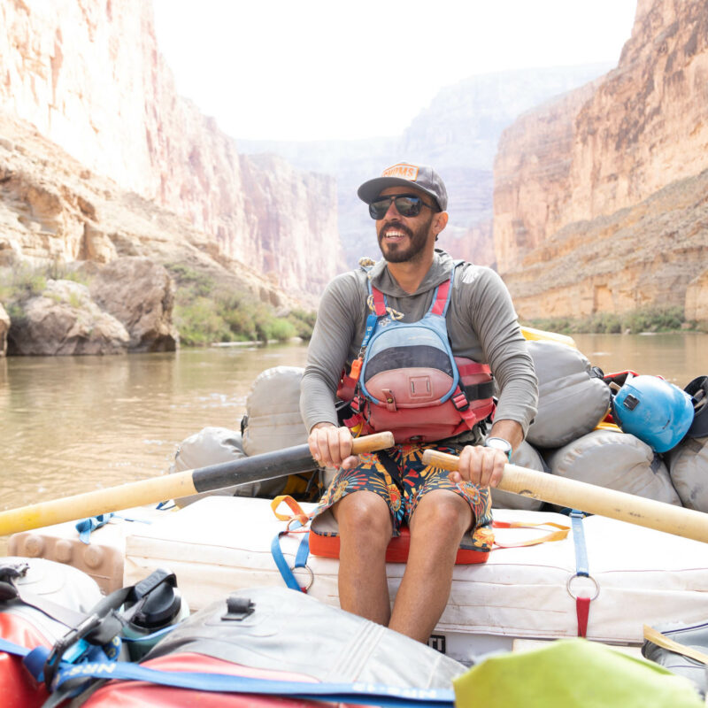 Guide rowing a raft through the Grand Canyon.