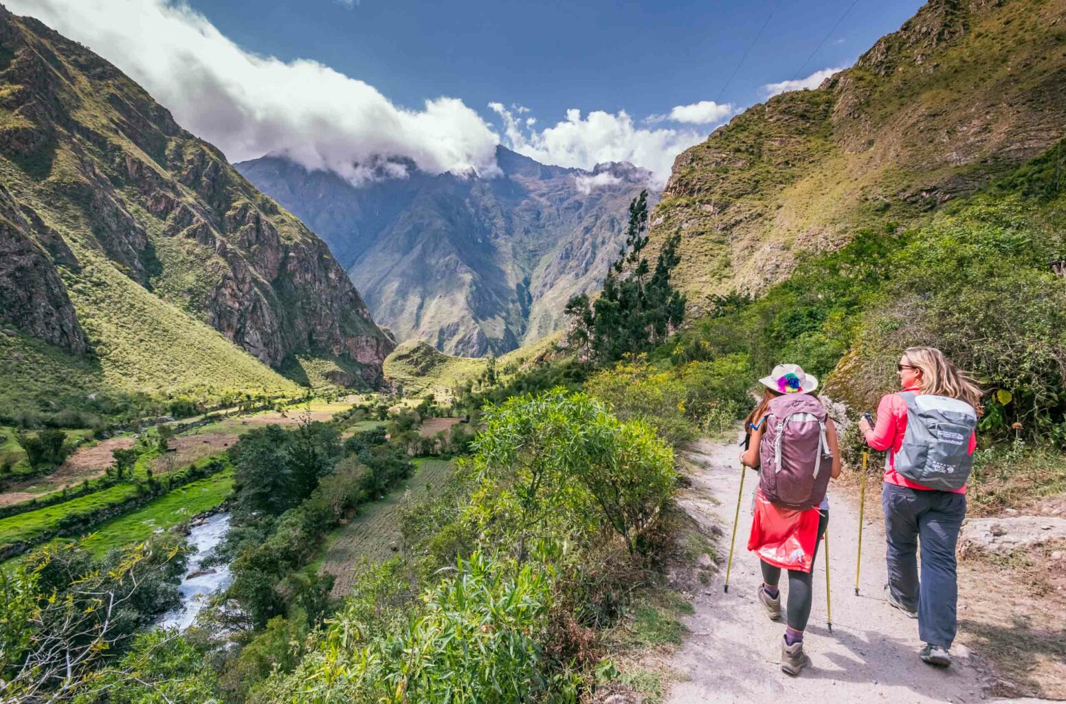 Two women hiking through a valley surrounded by mountains on Peru's Inca Trail to Machu Picchu.