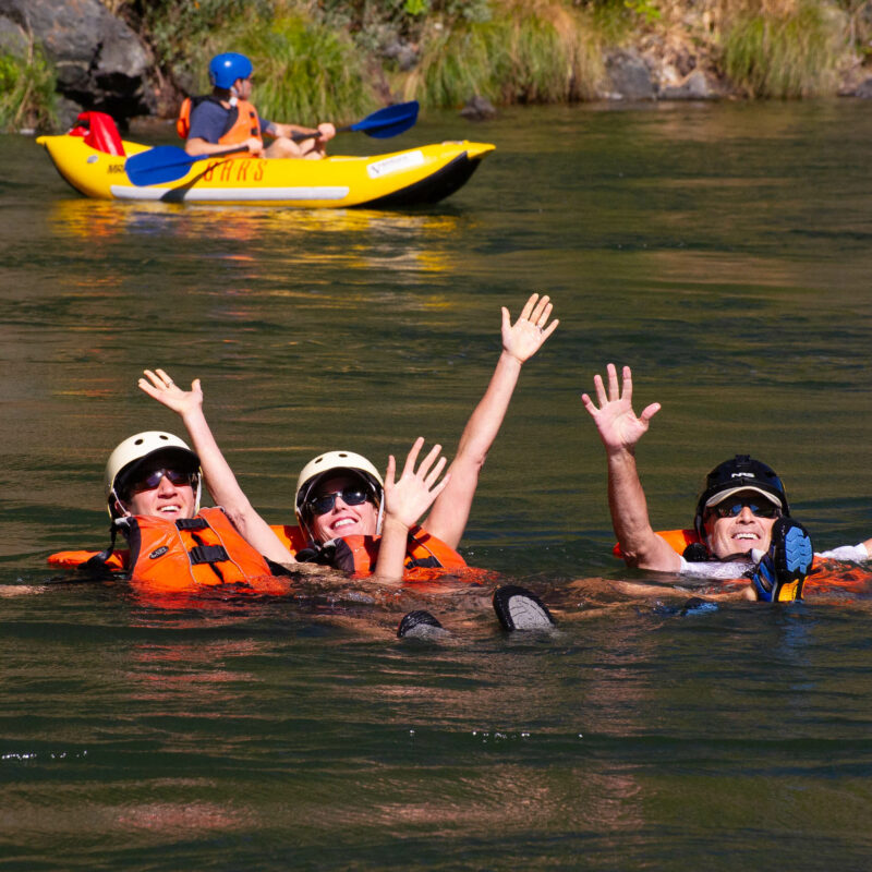 People floating and relaxing on the Rogue River with life vests.