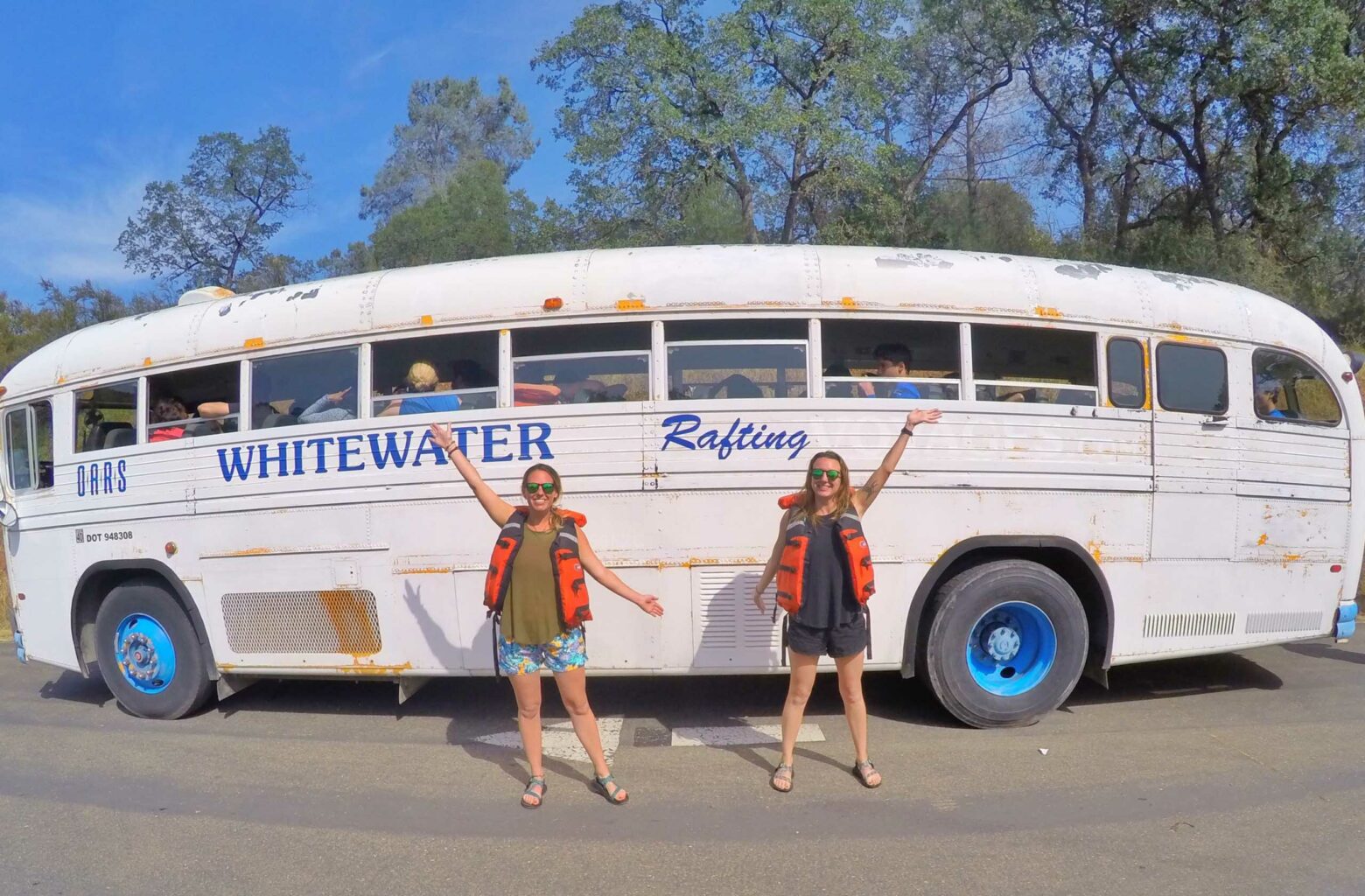 Two people posing in front the OARS Whitewater Rafting shuttle.