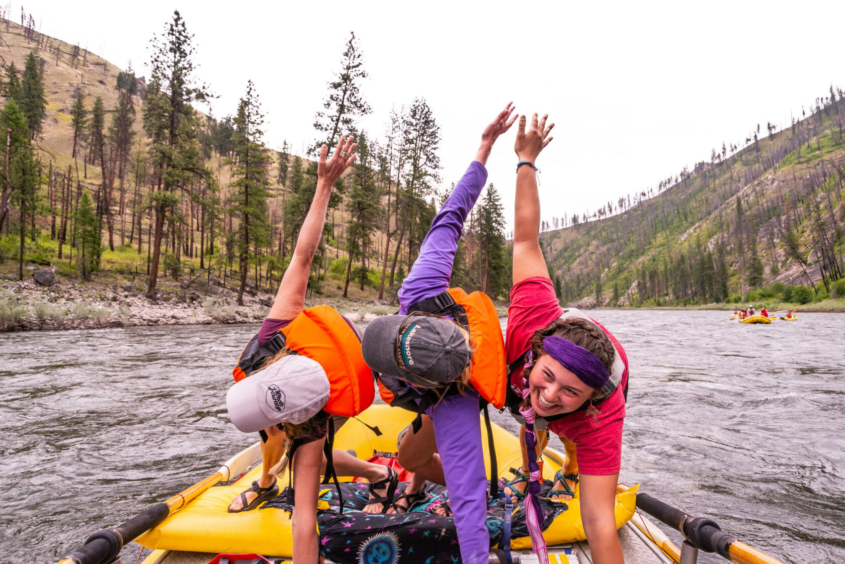 Three women doing yoga on a paddle board.