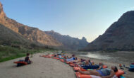 Group of travelers doing yoga on a river bank.
