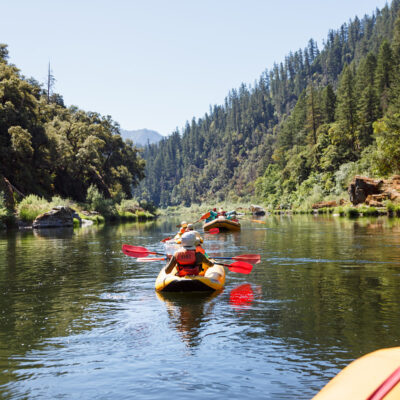 Yellow oar rafts and inflatable kayakers paddle down the Lower Klamath River