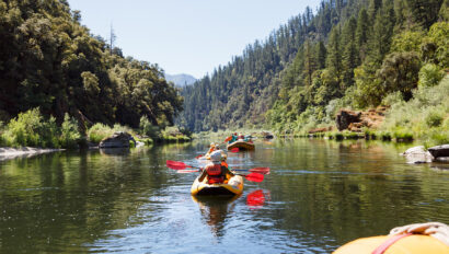 Yellow oar rafts and inflatable kayakers paddle down the Lower Klamath River