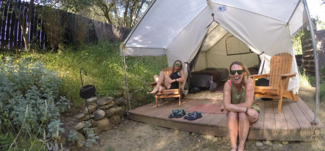 Two women sitting outside of their tent.