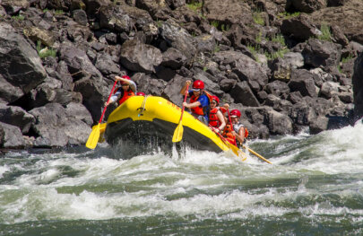 A raft full of smiling paddlers splashes through a rapid on the Lower Salmon River.