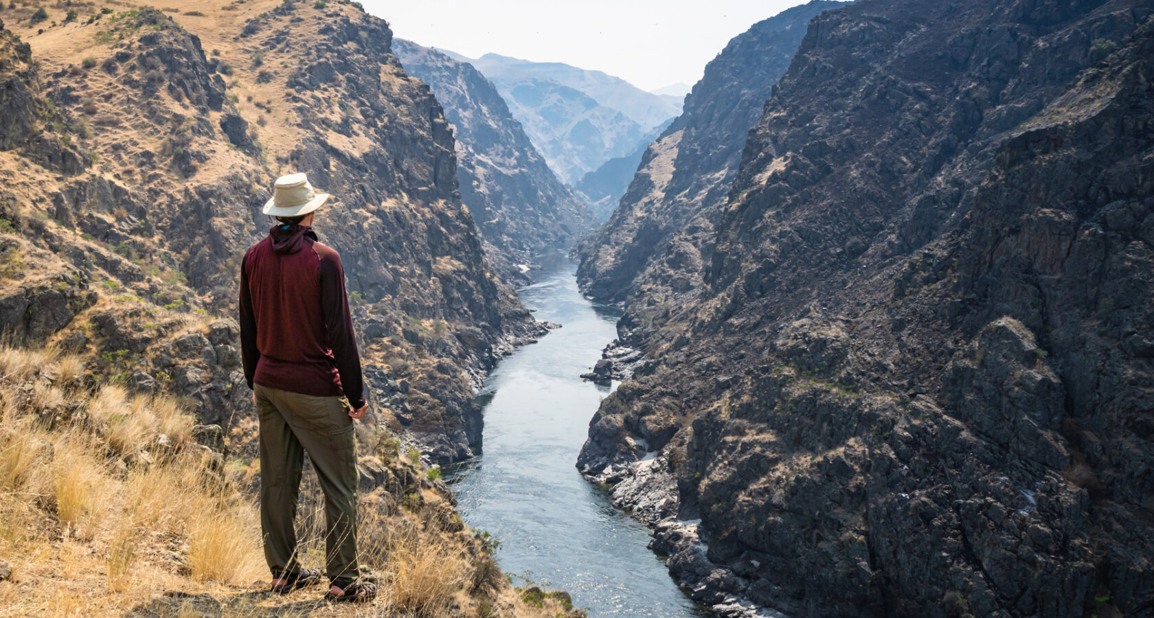 A hiker stands at a vista overlooking the Lower Salmon River and takes in the view.