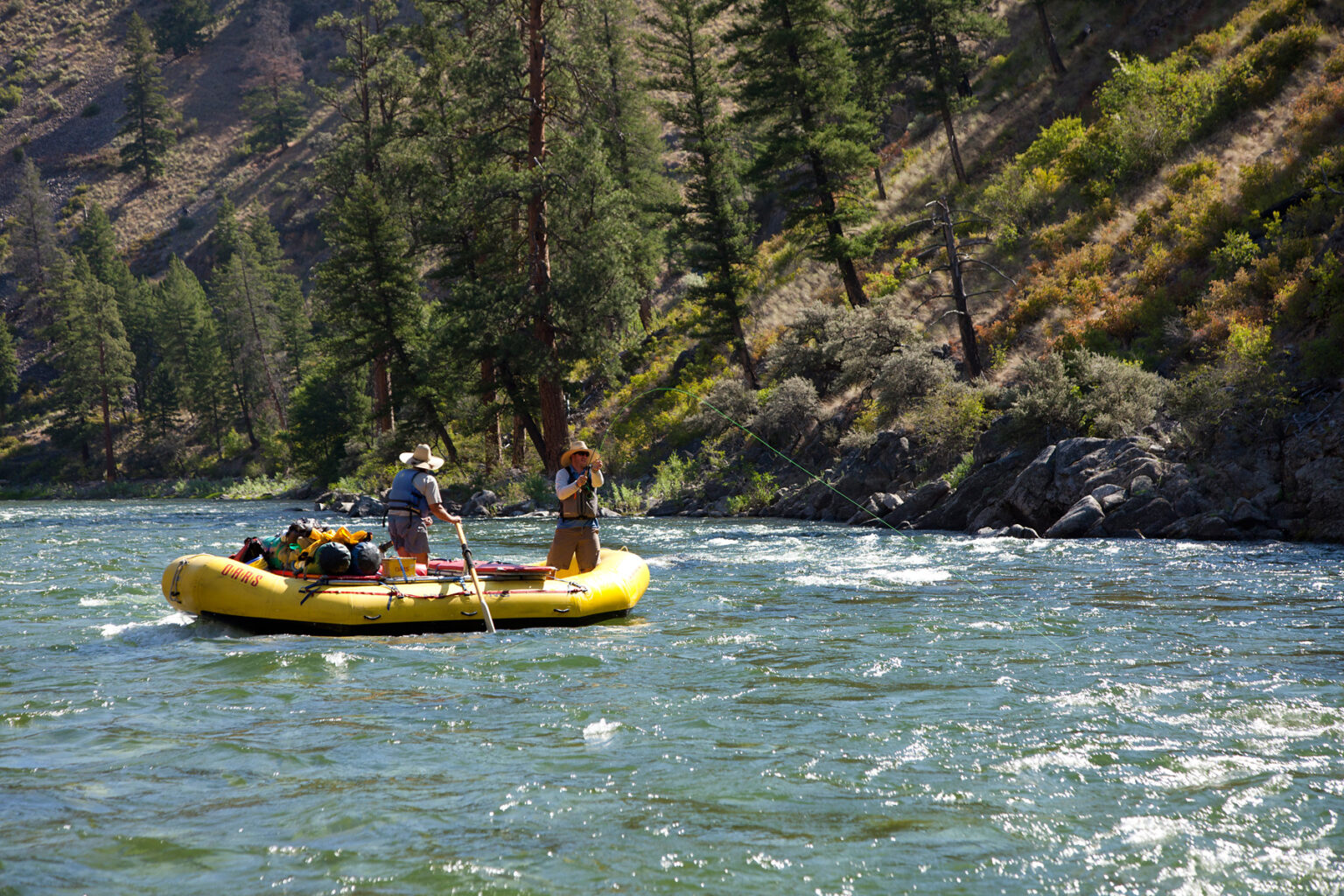 A fly fisherman rides in the front of an OARS raft on the Middle Fork of the Salmon River.