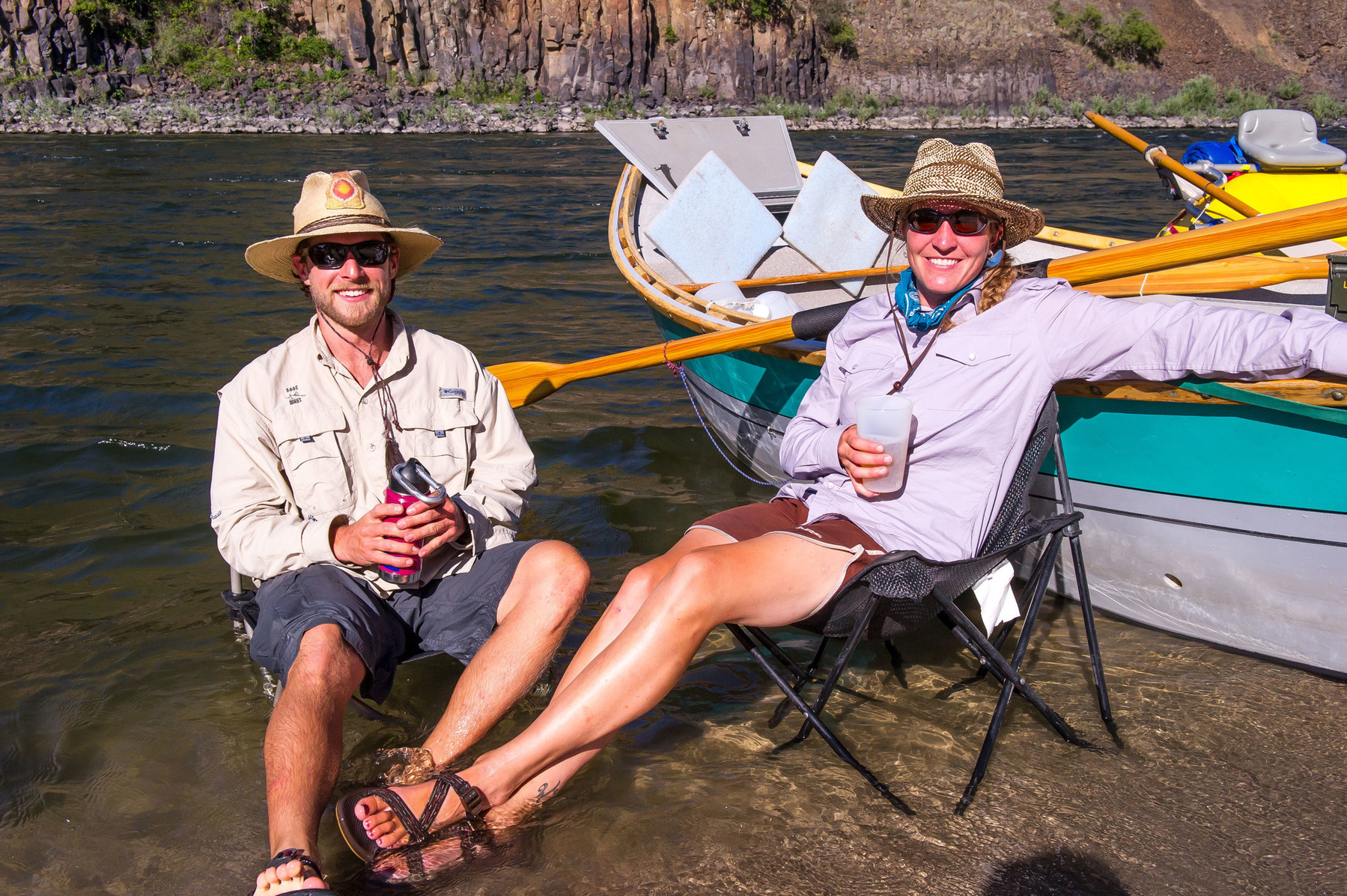Two adults sit in campchairs in the Lower Salmon River and smile at the camera on a craft beer trip.