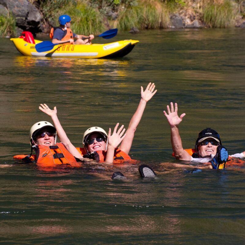 Three happy adults swim in the Rogue River on an OARS trip in Oregon.