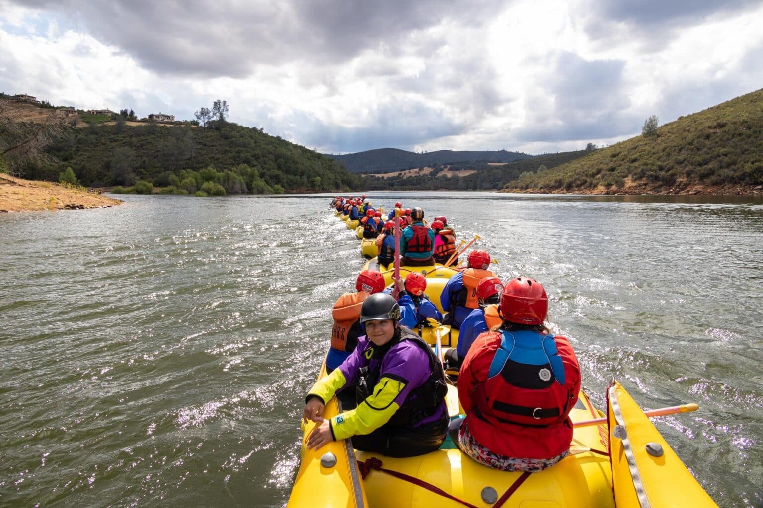 A group of young adults and youth being pulled to the take-out for South Fork American River rafting trips