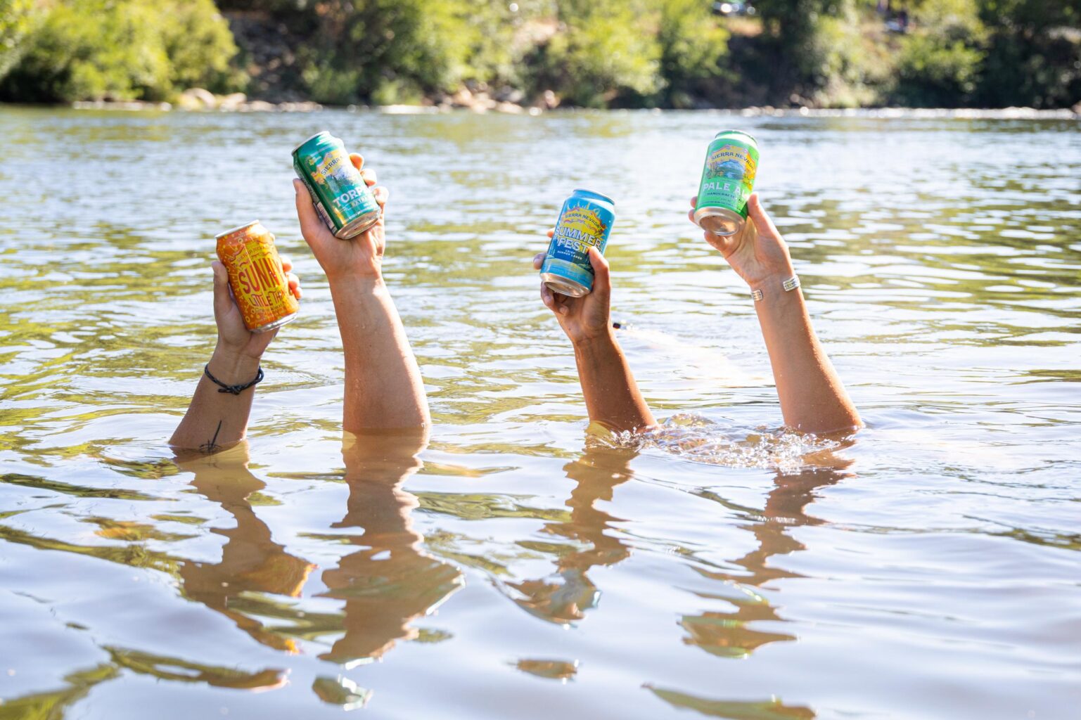 A group of OARS guides holding beers up from underwater.