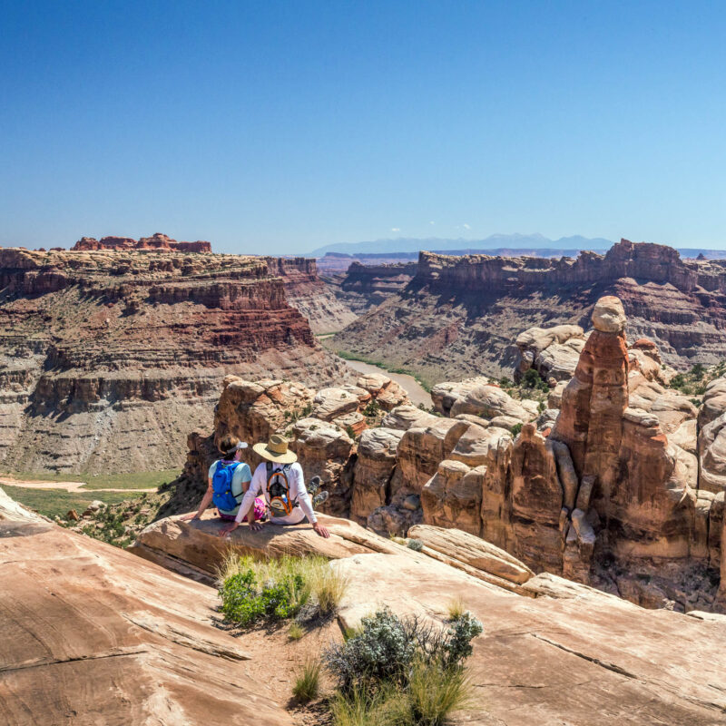 Two people sitting and overlooking Cataract Canyon.