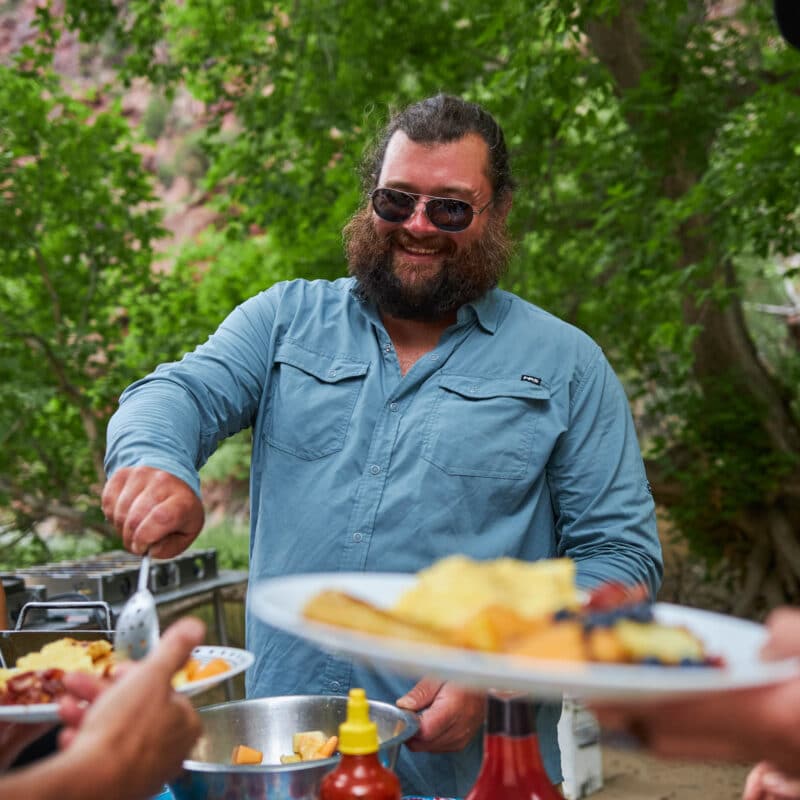 Guide serving food to guests on the Green River through Gates of Lodore trip.