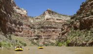 Two yellow OARS rafts full of people float down the Yampa River through a deep canyon in Dinosaur National Monument, Utah.