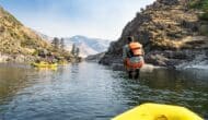 man in a life vest jumping off a raft into a river.