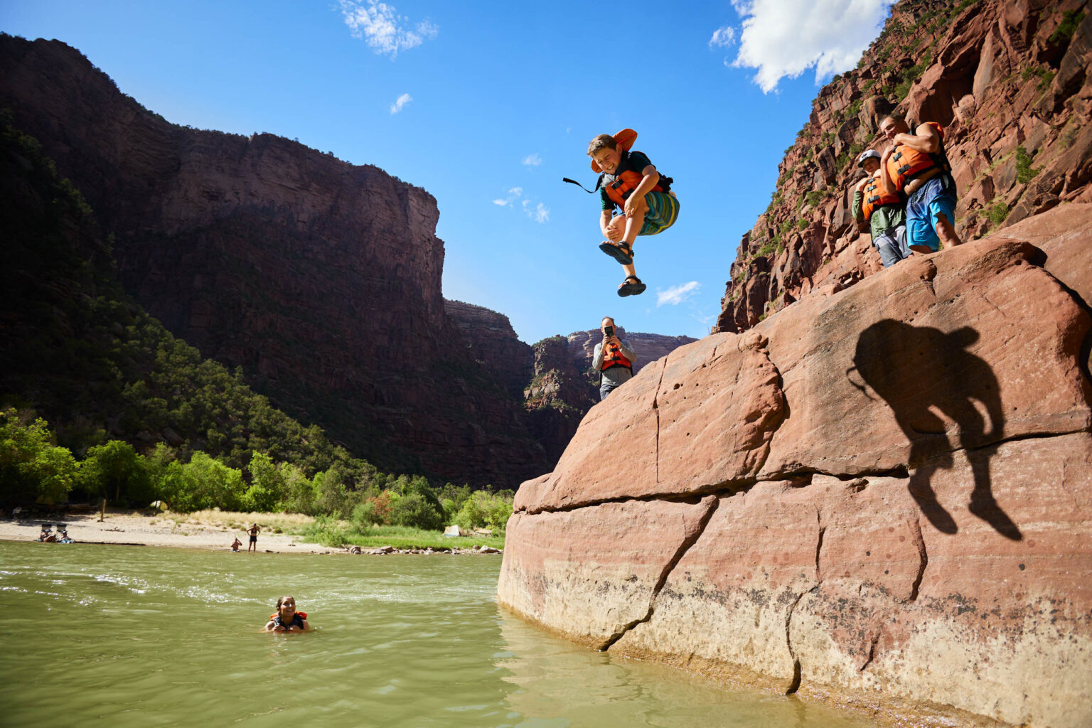 Kid jumping into a river from a rock.