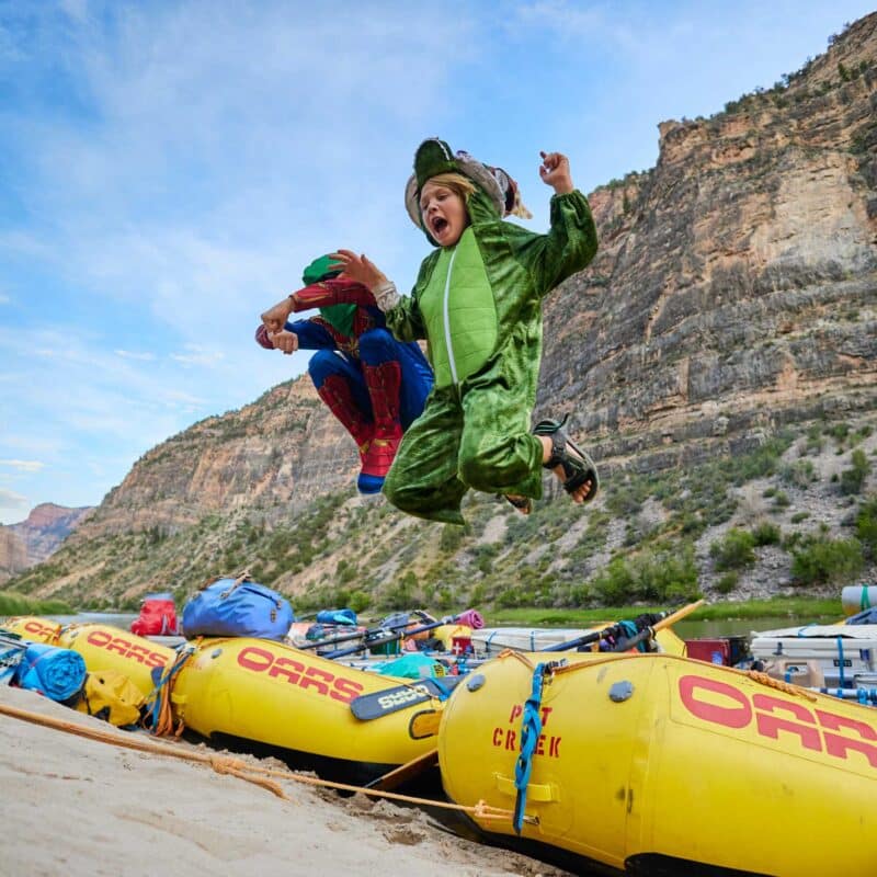two kids in costumes jumping off of rafts onto dry land.