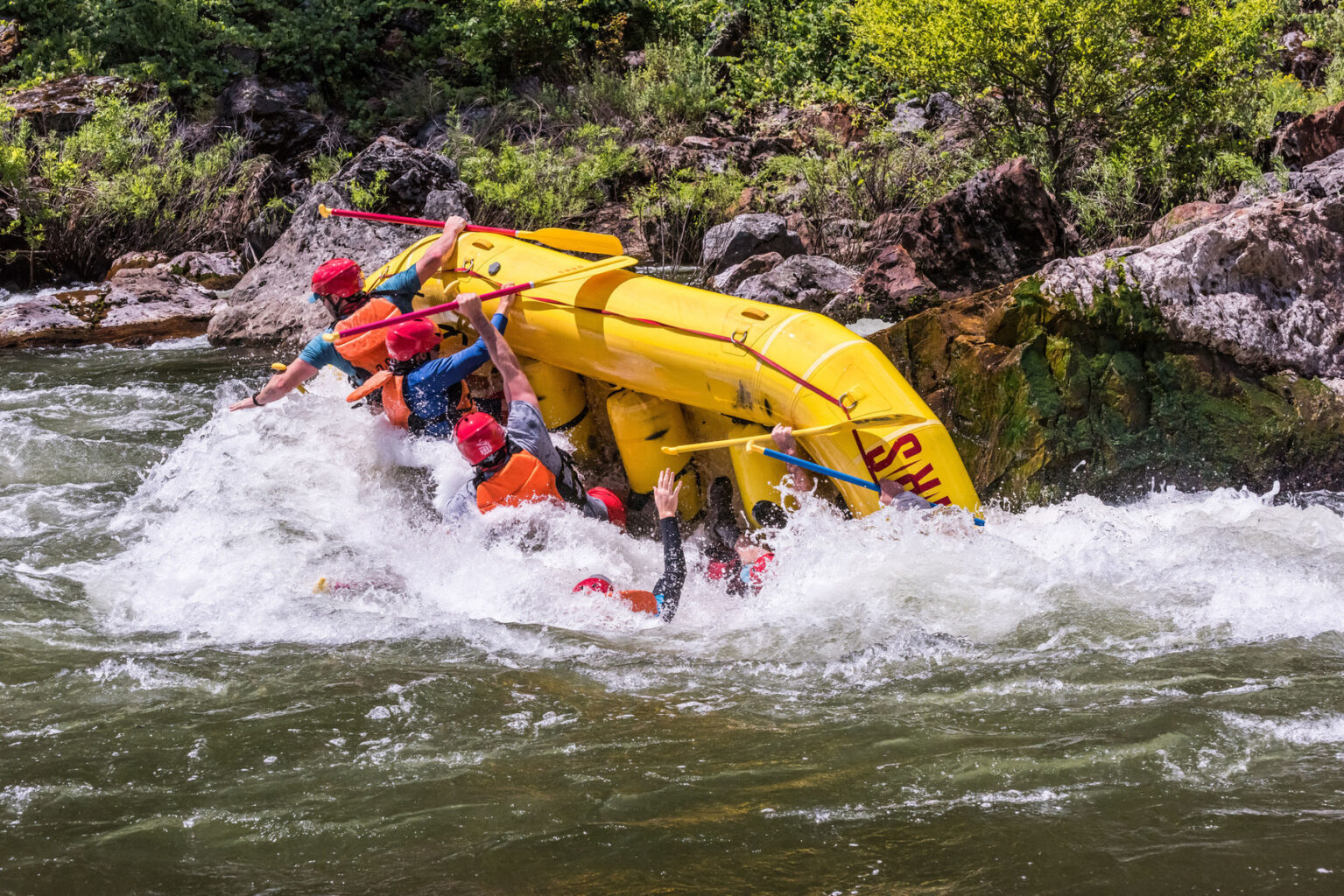 A yellow raft in mid-flip on the Tuolumne River trip in California as guests fall into the river