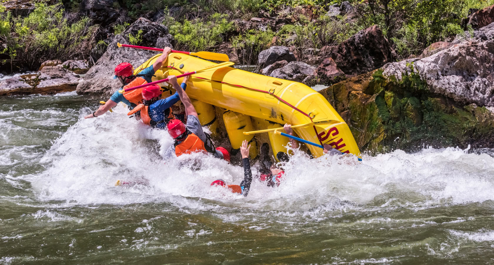 A yellow raft in mid-flip on the Tuolumne River trip in California as guests fall into the river