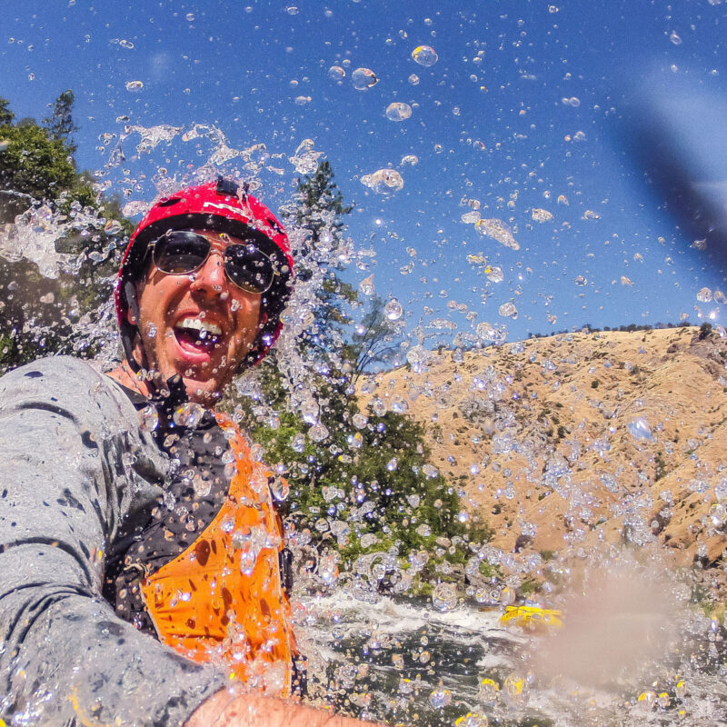 A man getting splashed in the face by whitewater on the Tuolumne River in California.