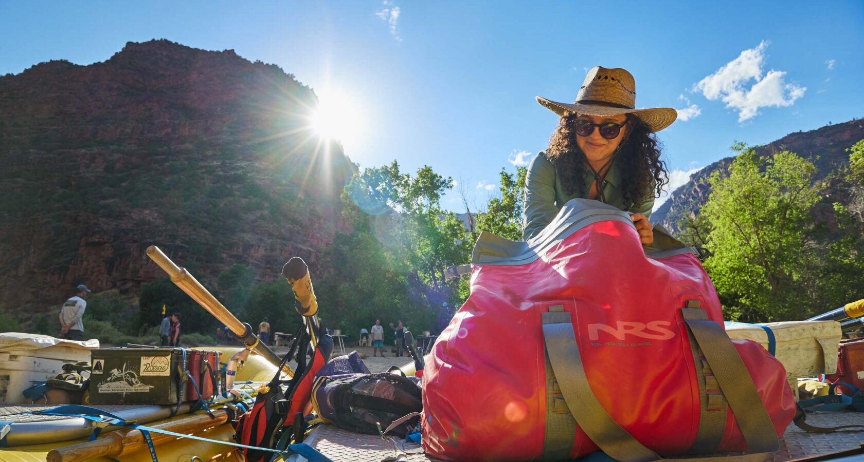 Woman in a hat packing a bag on a raft.
