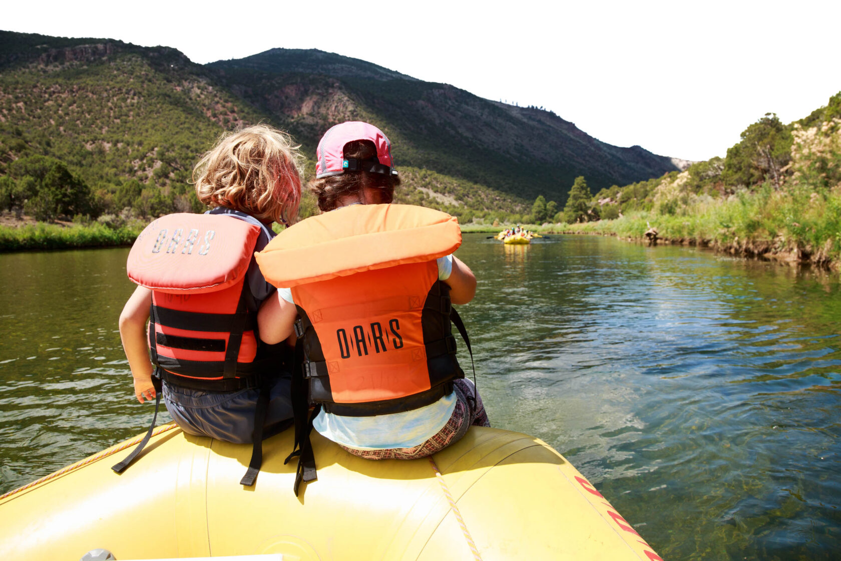 Two youths sitting on a raft together in the river.