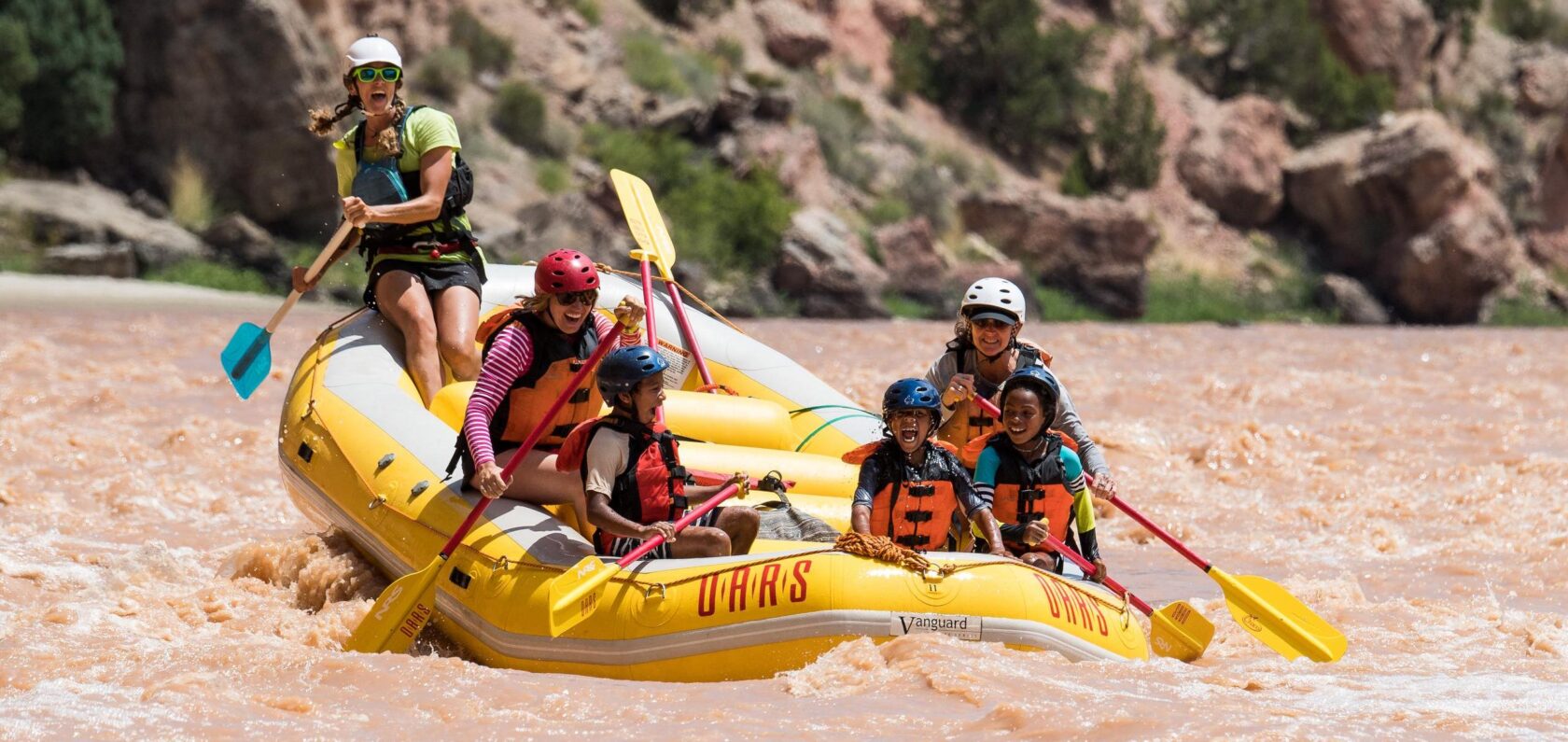 A family smiles as they raft Split Mountain Canyon in Utah