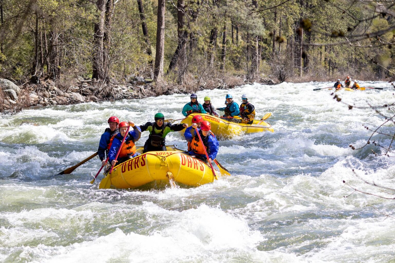 A group of paddlers in yellow boats rafting the Merced River in the spring 