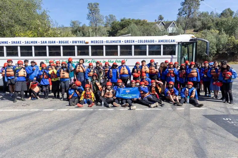 A group of students poses for ap hoto in front of an OARS bus. 