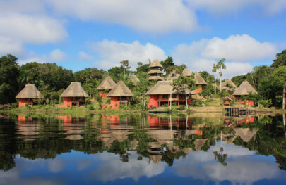 Bungalows sit along the water in a lush rainforest in the Amazon.